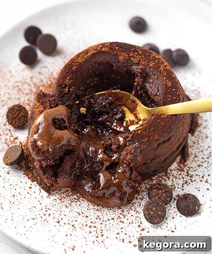 Gold spoon digging into Chocolate Lava Cake on a white plate with chocolate chips
