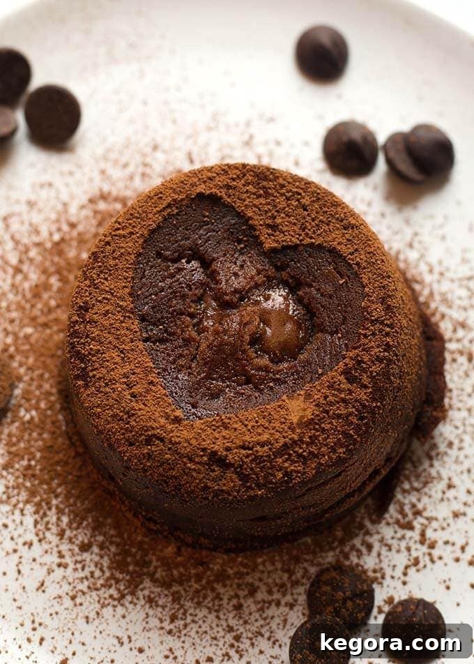 Chocolate Lava Cake with cocoa powder dusted heart all on a white plate with chocolate chips