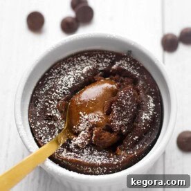 Chocolate Lava Cake in a white ramekin with golden spoon all on a light colored background