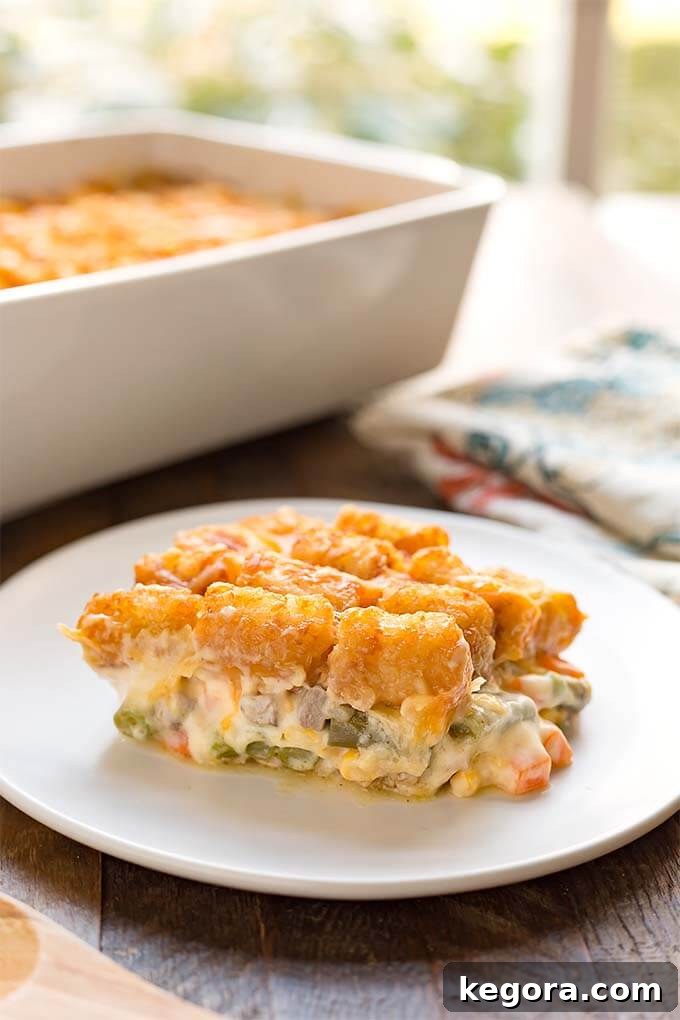 Crispy Tater Tot Comfort Casserole 4 Slice of Hotdish Tater Tot Casserole on a white plate in front of white baking dish