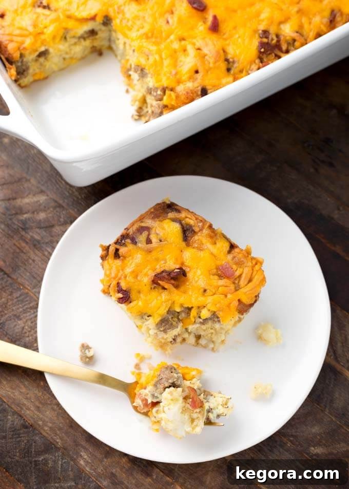 A delectable slice of Tater Tot Breakfast Casserole resting on a white plate, positioned in front of the full casserole dish.