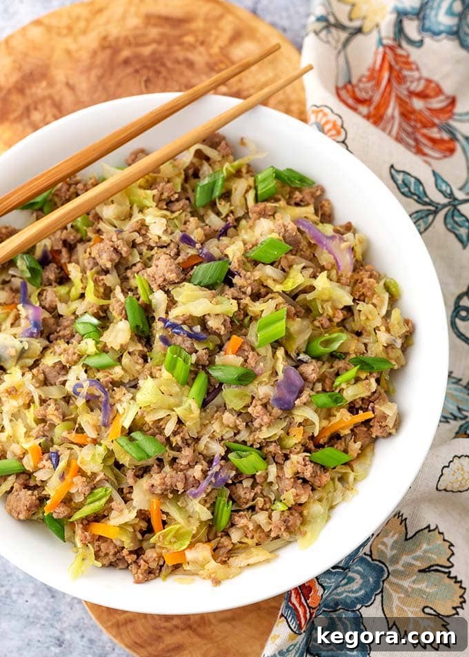A vibrant Instant Pot Egg Roll in a Bowl served in a white ceramic bowl, garnished with fresh green onions and ready to be enjoyed with bamboo chopsticks.