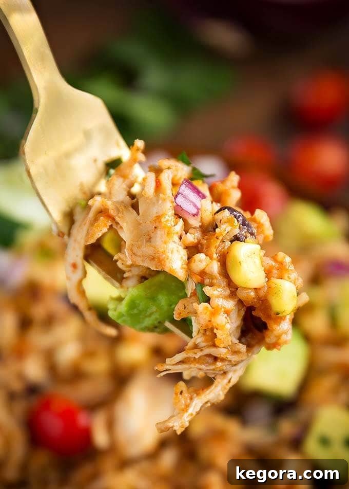 Closeup of a forkful of Instant Pot Chicken Taco Bowls, showing the texture of the rice, chicken, and colorful toppings.