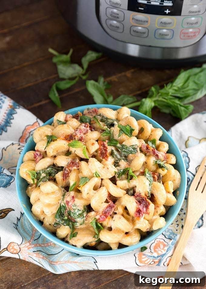 Tuscan Chicken Pasta in a blue bowl in front of a pressure cooker