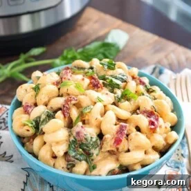 Tuscan Chicken Pasta in a blue bowl in front of a pressure cooker