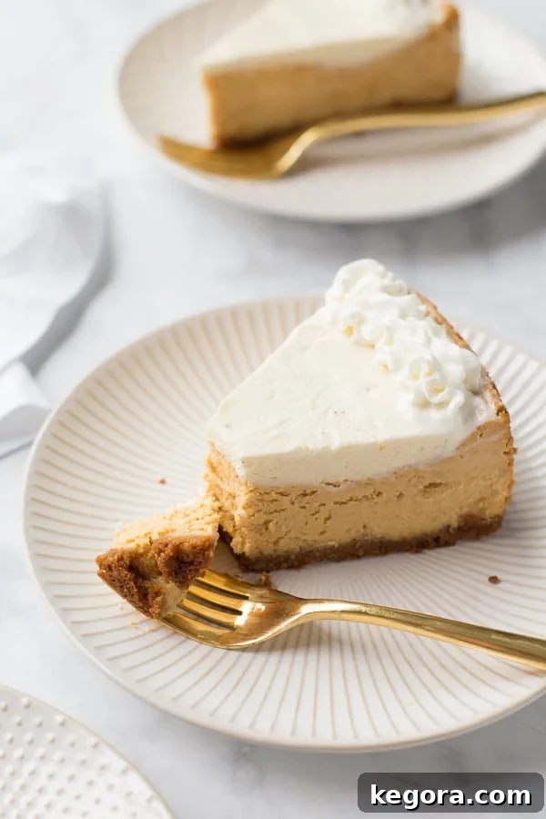 Decadent Gluten-Free Pumpkin Cheesecake 2 A slice of gluten-free pumpkin cheesecake on a white plate with a gold fork, showcasing its creamy layers.