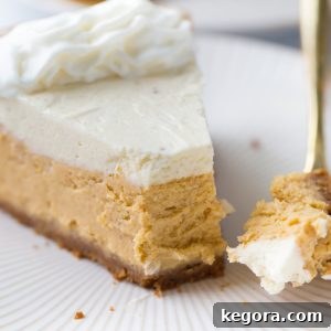 Close-up shot of pumpkin cheesecake on a white plate with a gold fork, showcasing its creamy texture.