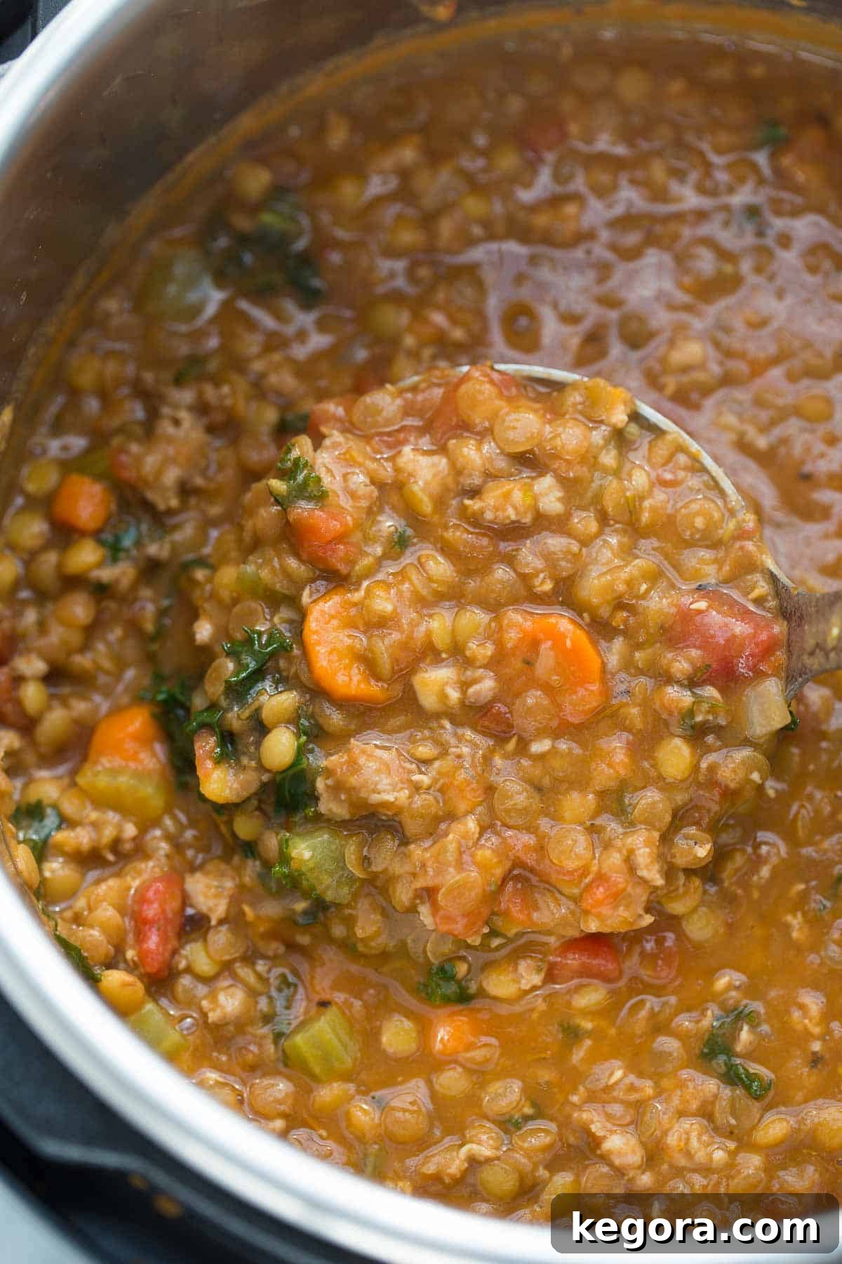 Hearty Sausage Lentil Soup 2 Büyük bir kaşıkla servis edilen sosisli mercimek çorbasının yakın çekim görüntüsü, dumanı tütüyor ve doyurucu bir his veriyor.