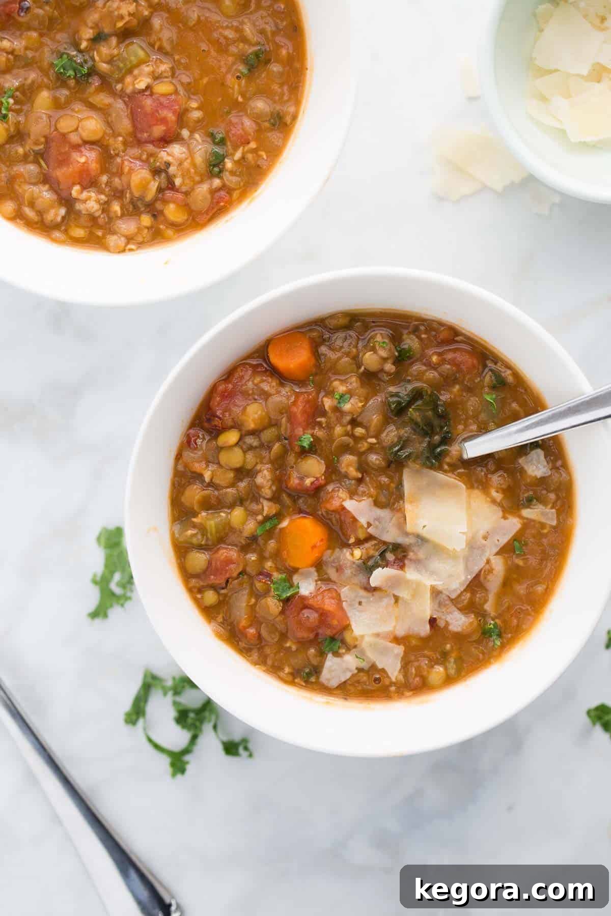 Bowl of sausage lentil soup topped with grated parmesan cheese and fresh parsley.
