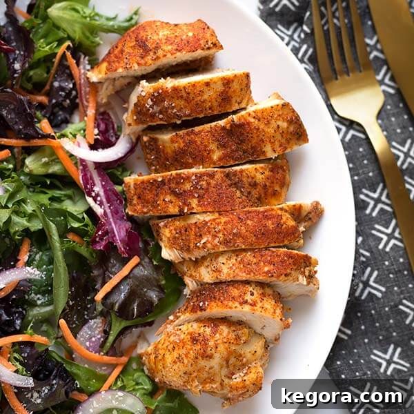 Sliced tender chicken breast with fresh vegetables on a white plate, showcasing a healthy and easy Instant Pot meal.