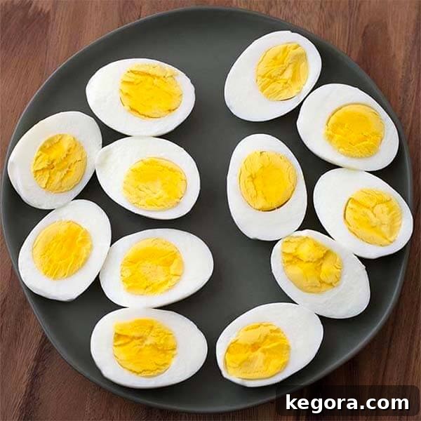 Several perfectly boiled eggs, sliced neatly in half, arranged on a sleek black plate.