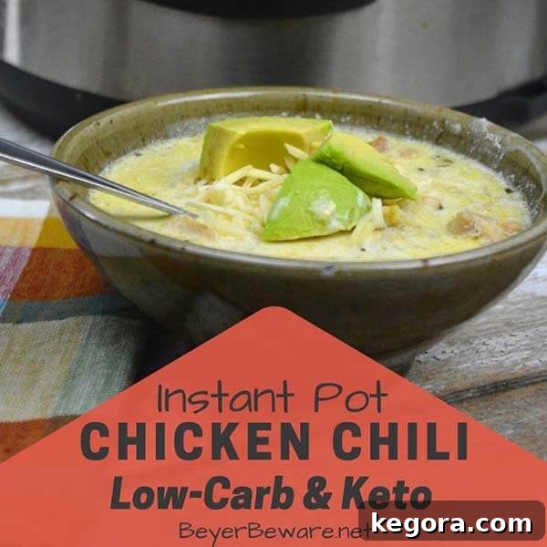 Hearty chicken chili in an olive-green bowl with a spoon, placed in front of an Instant Pot, depicting a comforting low-carb meal.