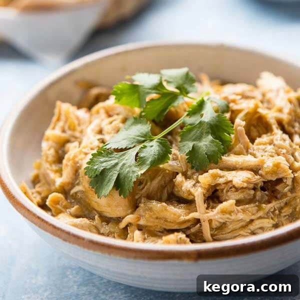 A bowl of vibrant green Instant Pot Chicken Chili, garnished with fresh green herbs, presented in a white bowl with a brown rim.