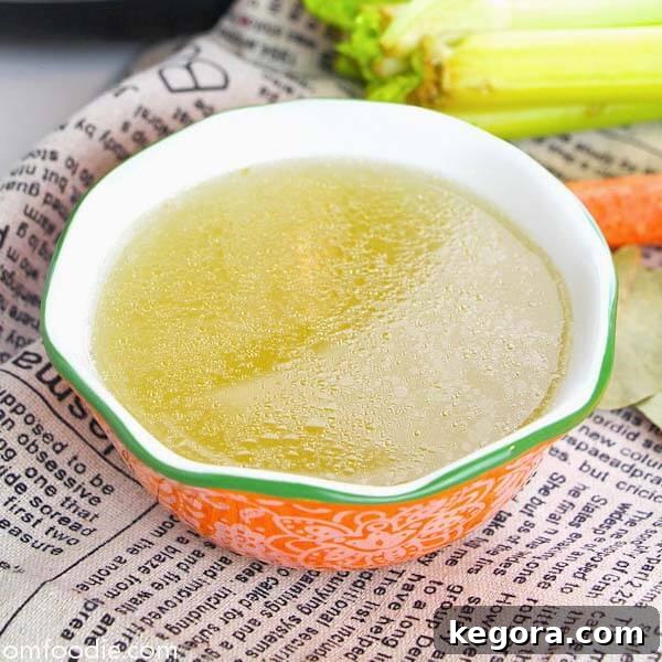 Nourishing Instant Pot Easy Chicken Bone Broth served in an orange bowl with a green rim, resting on a newsprint-style napkin.