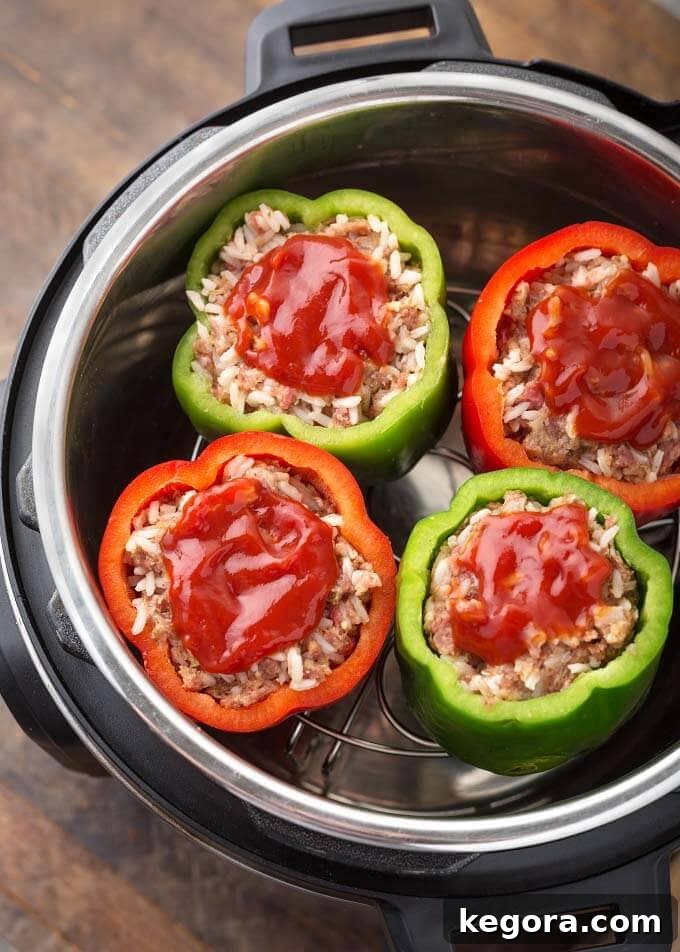 Four Instant Pot Stuffed Peppers topped with a dollop of ketchup on a trivet in a pressure cooker