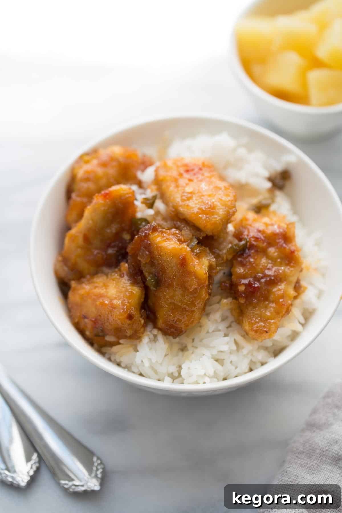 Sticky Chicken A bowl of glossy, golden-brown sticky chicken served over fluffy white rice, garnished with fresh herbs.