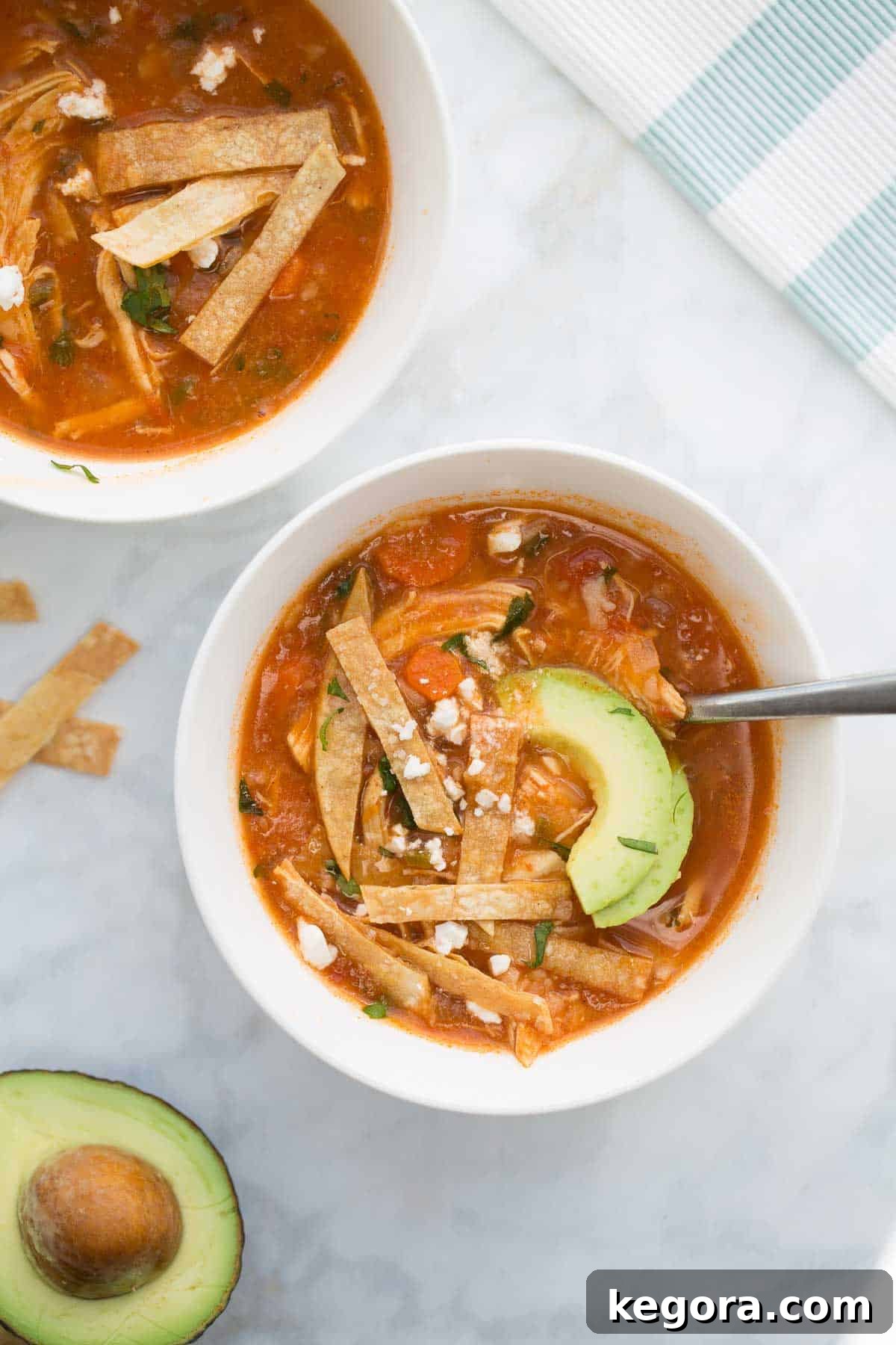 Ultimate Instant Pot Chicken Tortilla Soup 3 2 serving bowls of chicken tortilla soup with toppings of avocado and corn tortilla strips