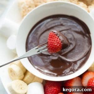strawberry being dipped into white bowl of chocolate fondue