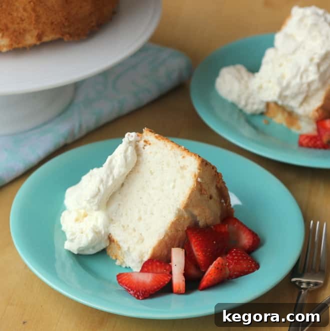 A delightful slice of angel food cake presented on a charming blue plate, generously topped with fresh strawberries and a dollop of fluffy whipped cream.