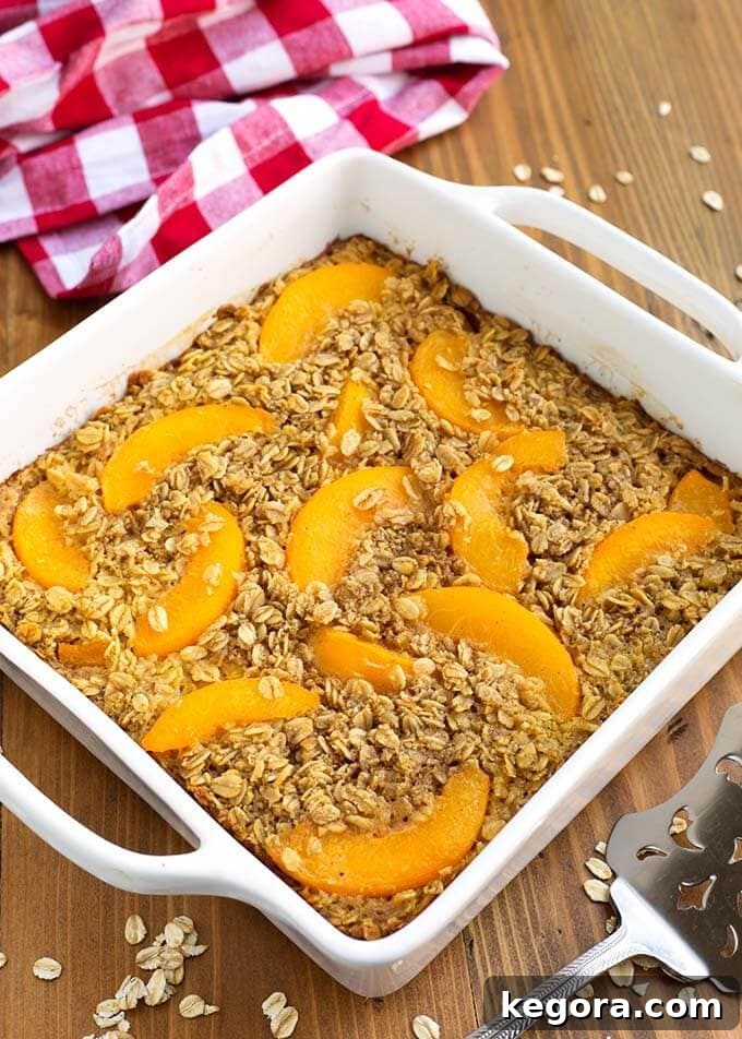 Peach Baked Oatmeal in a white square baking dish next to a red gingham napkin