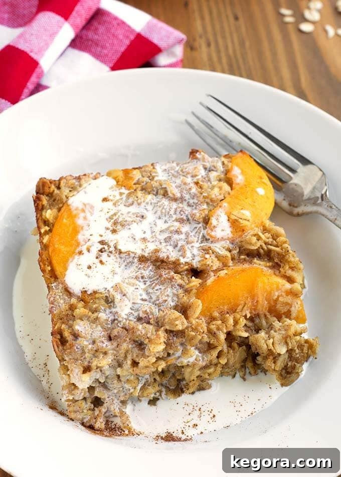 Slice of Easy Peach Baked Oatmeal on a white plate with a silver fork
