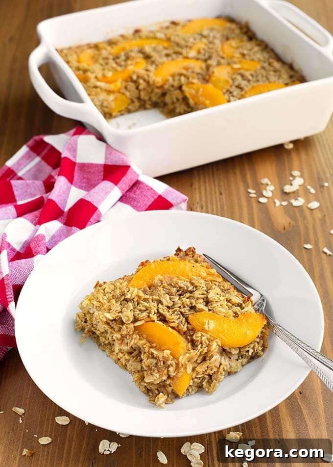 Slice of Easy Peach Baked Oatmeal with a fork on a white plate in front of white baking dish with rest of peach baked oatmeal
