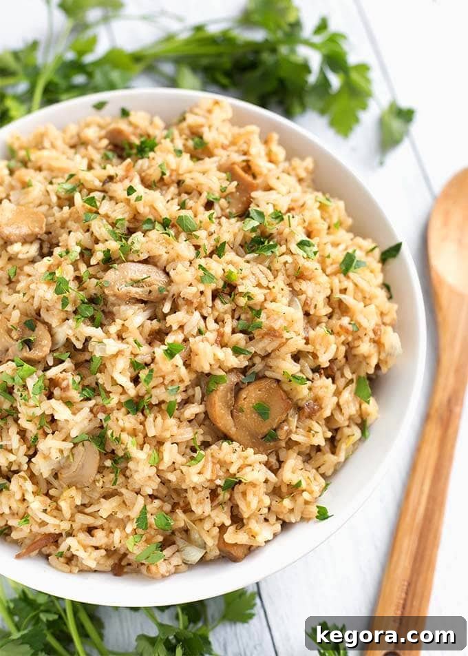 Top view of French Onion Rice in a white bowl next to a wooden spoon