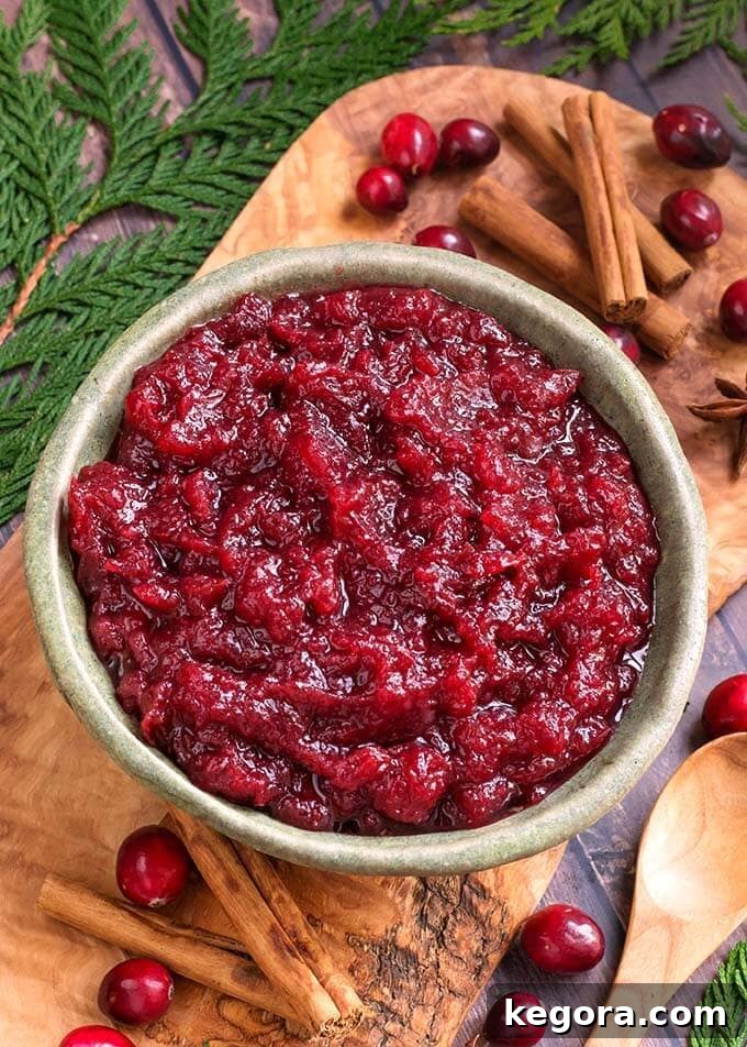 Set It and Forget It Cranberry Sauce 3 Homemade Cranberry Sauce in a vibrant green bowl, garnished with festive greenery