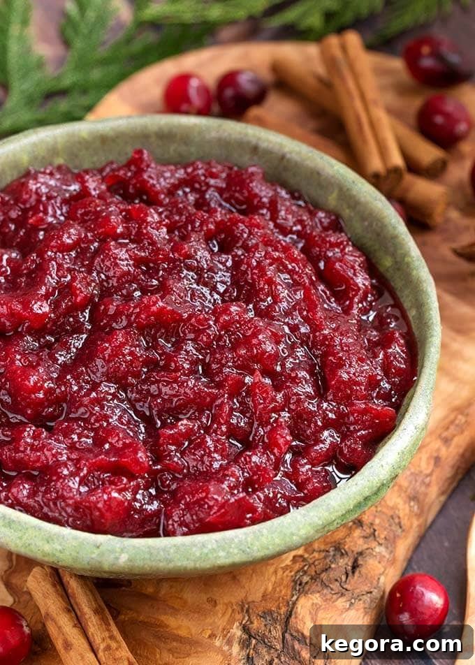 Set It and Forget It Cranberry Sauce 8 Bowl of Slow Cooker Cranberry Sauce on a rustic wooden plank, highlighting its homemade appeal