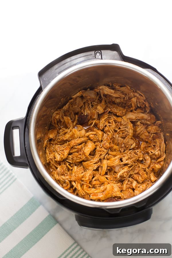 Overhead shot of Instant Pot BBQ chicken in the pot, freshly shredded and coated in sauce