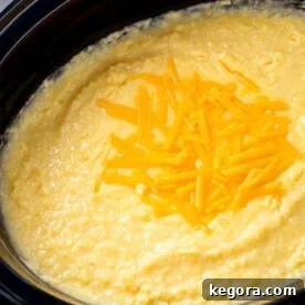 Effortless Slow Cooker Cheesy Grits 11 Cheesy Grits in a slow cooker topped with shredded cheese, ready to be served.