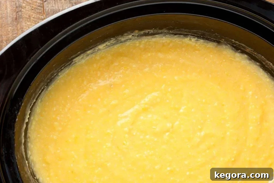 Effortless Slow Cooker Cheesy Grits 8 Cooked Slow Cooker Cheesy Grits simmering in a black crock pot.