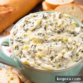 Instant Pot Spinach Artichoke Dip in a turquoise serving bowl next to slices of toasted bread