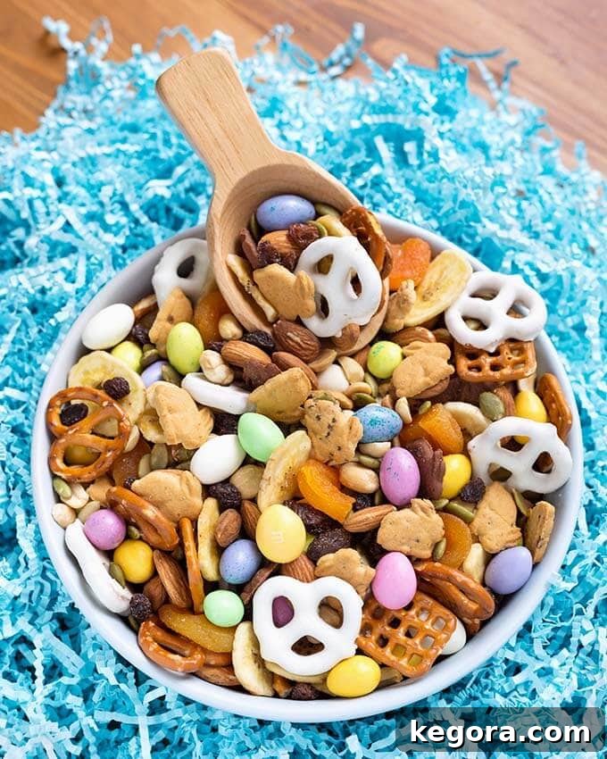 Easter Bunny's Munchie Medley 2 Bunny Bait Easter Trail Mix in a white bowl with wooden serving spoon on blue confetti paper