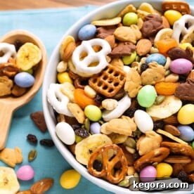 Easter Bunny's Munchie Medley 6 Bunny Bait Easter Trail Mix in a white bowl next to a wooden serving spoon all on a blue napkin