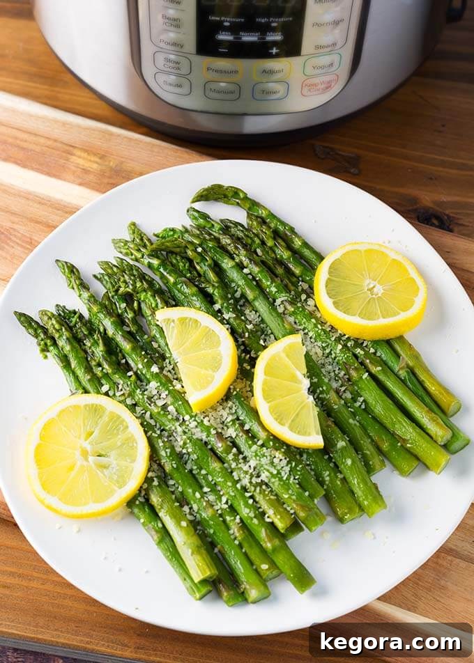 Perfectly cooked Instant Pot Asparagus on a white plate with fresh lemon slices, set in front of a modern pressure cooker, ready to be served as a delightful side dish.