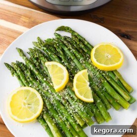 Asparagus on a white plate with lemon slices, a perfect visual representation of the Instant Pot Asparagus recipe.