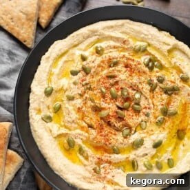 Hummus in black bowl next to cut pieces of flatbread