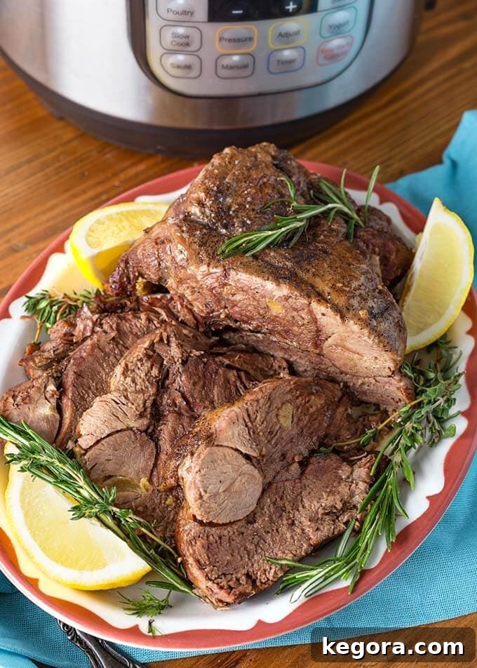 Tender Instant Pot Leg of Lamb 4 Leg of Lamb garnished with rosemary and lemons on red bordered plate in front of pressure cooker