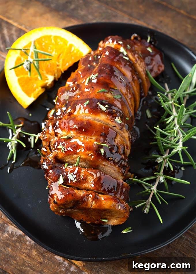 More sliced Honey Garlic Pork Tenderloin with fresh rosemary garnish on black plate