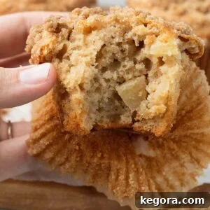 Close up photo of the interior of a gluten-free apple muffin, showing the fluffy texture and pieces of apple.