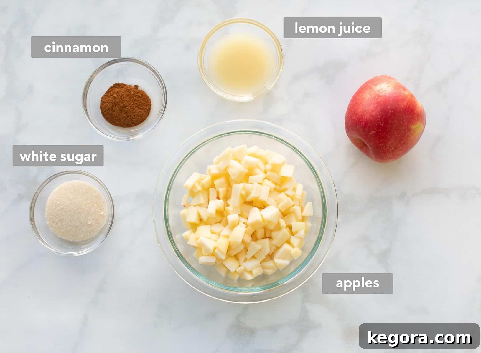 Chopped apples, lemon juice, sugar, and cinnamon arranged on a counter, ready for the apple mixture.