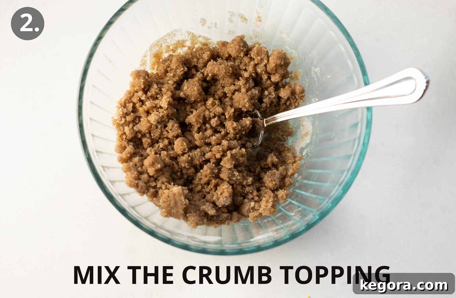 A glass bowl with crumb topping ingredients and a spoon