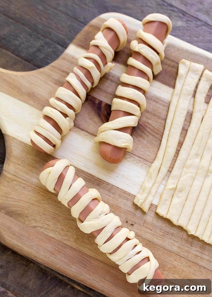 Fright Night Frank Wraps 5 Hot dogs wrapped with dough on wooden board