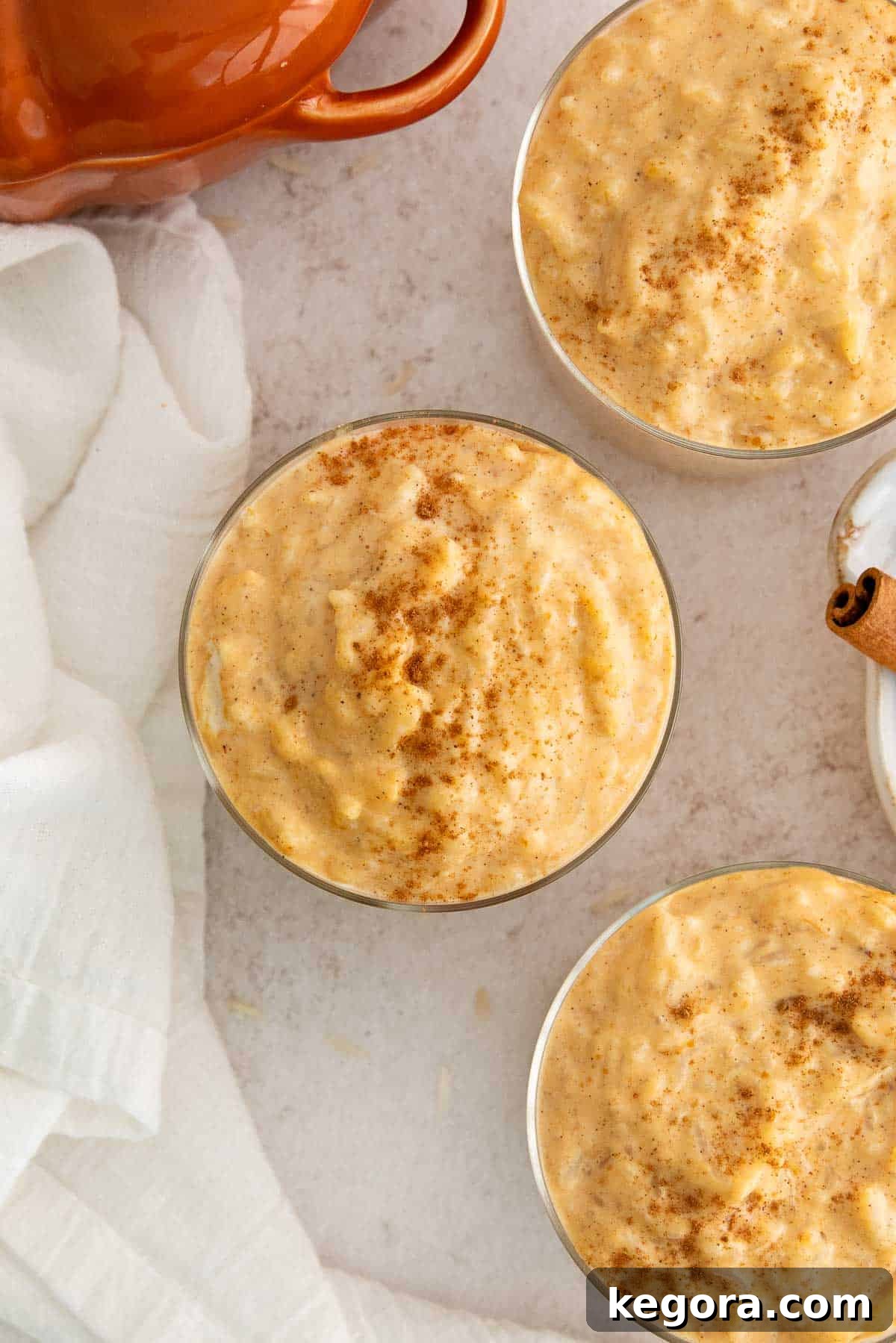 Spiced Pumpkin Rice Pudding 7 An inviting overhead view of multiple glass bowls filled with creamy pumpkin rice pudding, each elegantly garnished with a sprinkle of autumn spices.