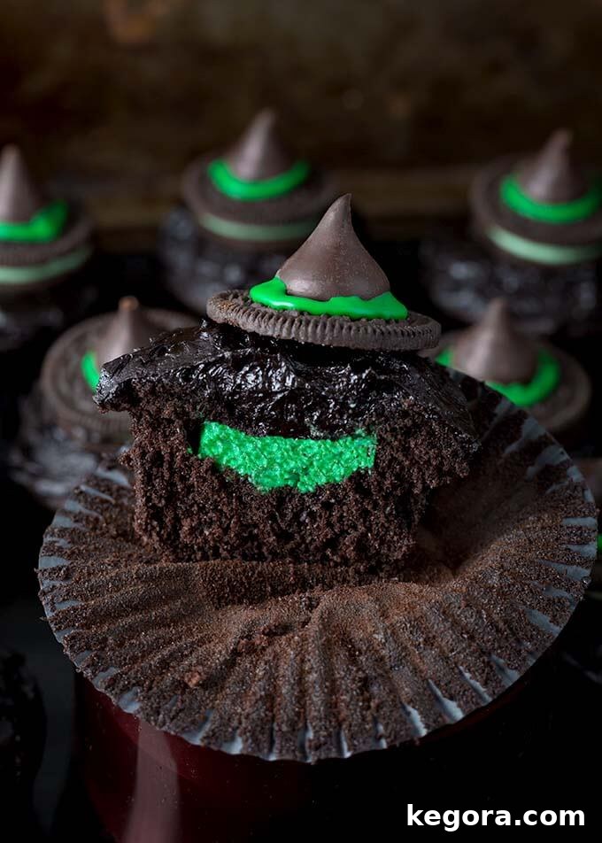 Closeup showing inside of Dark Chocolate Halloween Witch Hat Cupcakes, revealing the vibrant green cream cheese filling