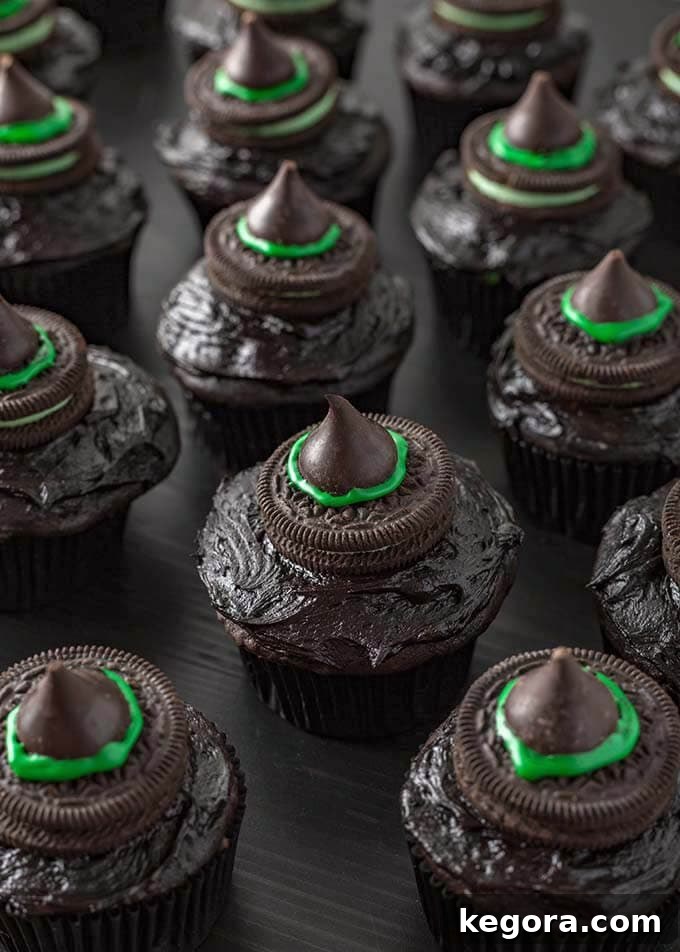 Several Halloween Witch Hat Cupcakes on dark wood board, highlighting the finished witch hat decorations with green bands