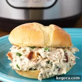 Instant Pot Creamy Dream Chicken 6 Crack Chicken on hamburger bun on blue plate in front of pressure cooker