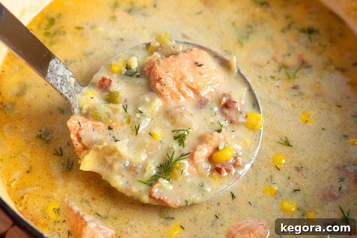 Artisan Salmon Chowder 3 A wooden ladle lifting a generous portion of Salmon Chowder from a large pot, showcasing the creamy broth and chunky ingredients.