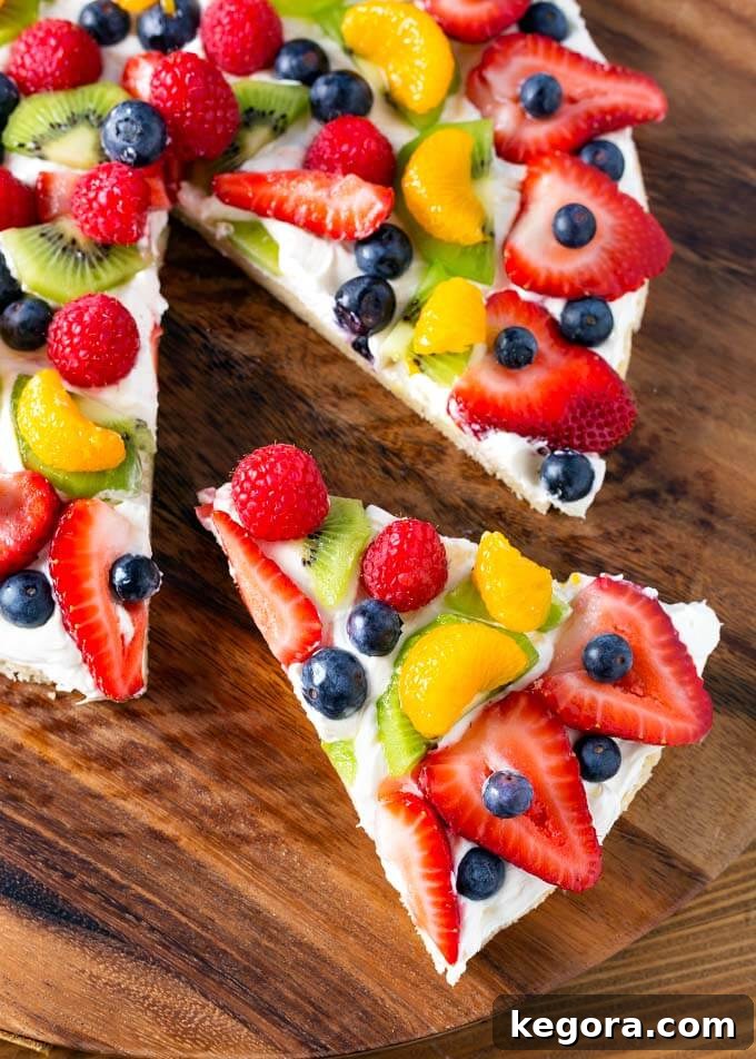 A slice of Fresh Fruit Pizza being carefully removed from the whole dessert